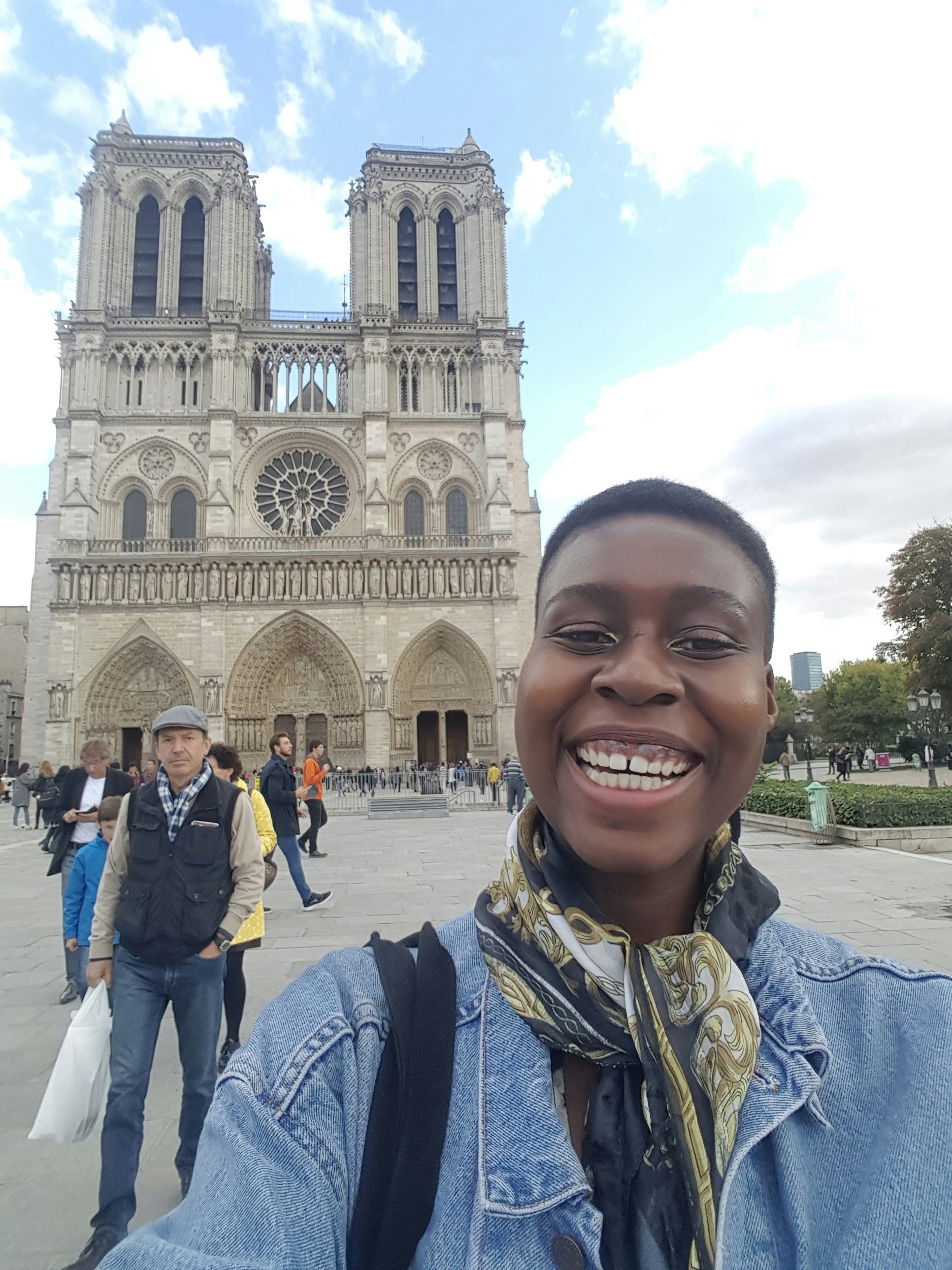 A black woman smiles in front of the cathedral of Notre Dame in Paris